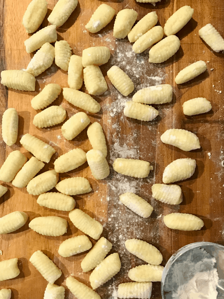 uncooked gnocchi, shaped and on a wooden cutting board