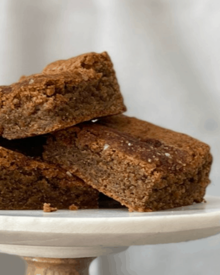 three coffee spice blondies stacked on marble and wood cake stand