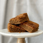 three coffee spice blondies stacked on marble and wood cake stand