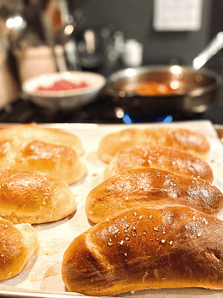8 baked brioche buns on parchment in front of saute pan