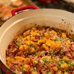 red dutch oven filled with farro, butternut squash and bacon
