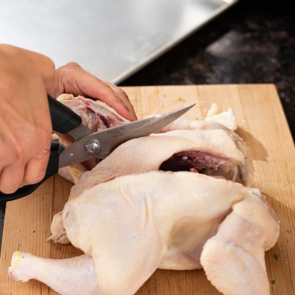 cutting other side of raw chicken backbone