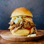 pulled pork and coleslaw sandwich on wood plate