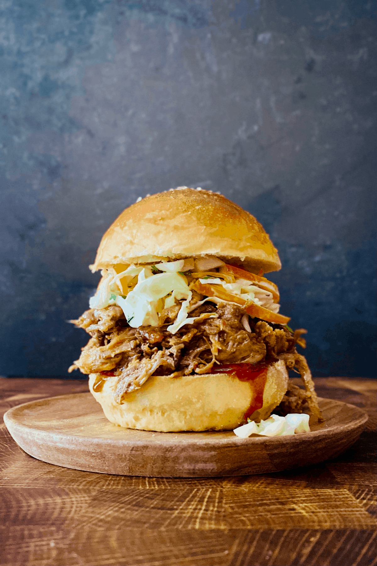 pulled pork and coleslaw sandwich on wood plate