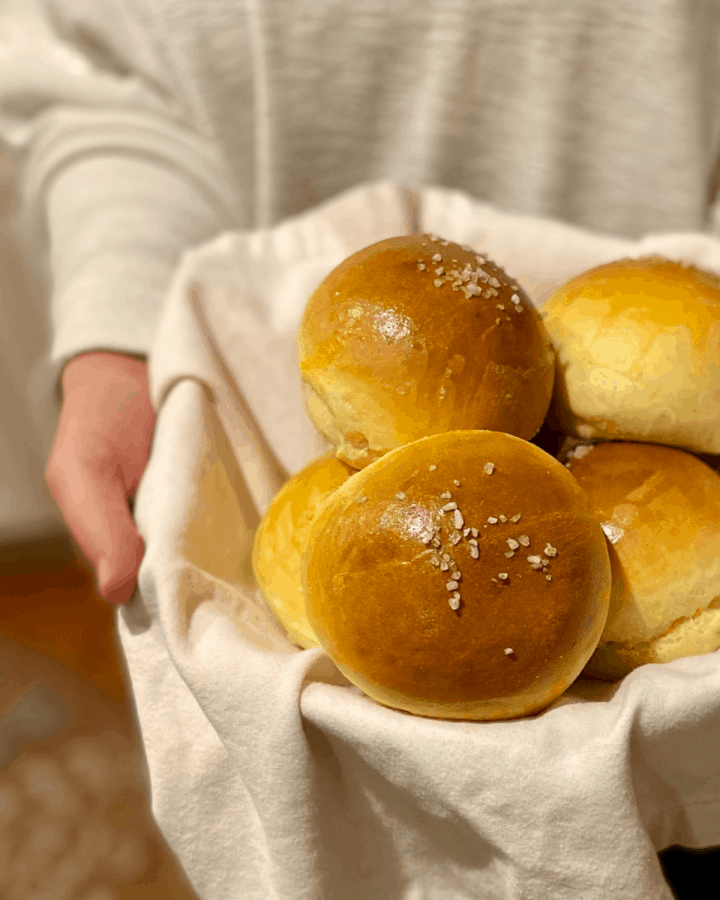 hand holding 5 brioche buns in napkin lined basket