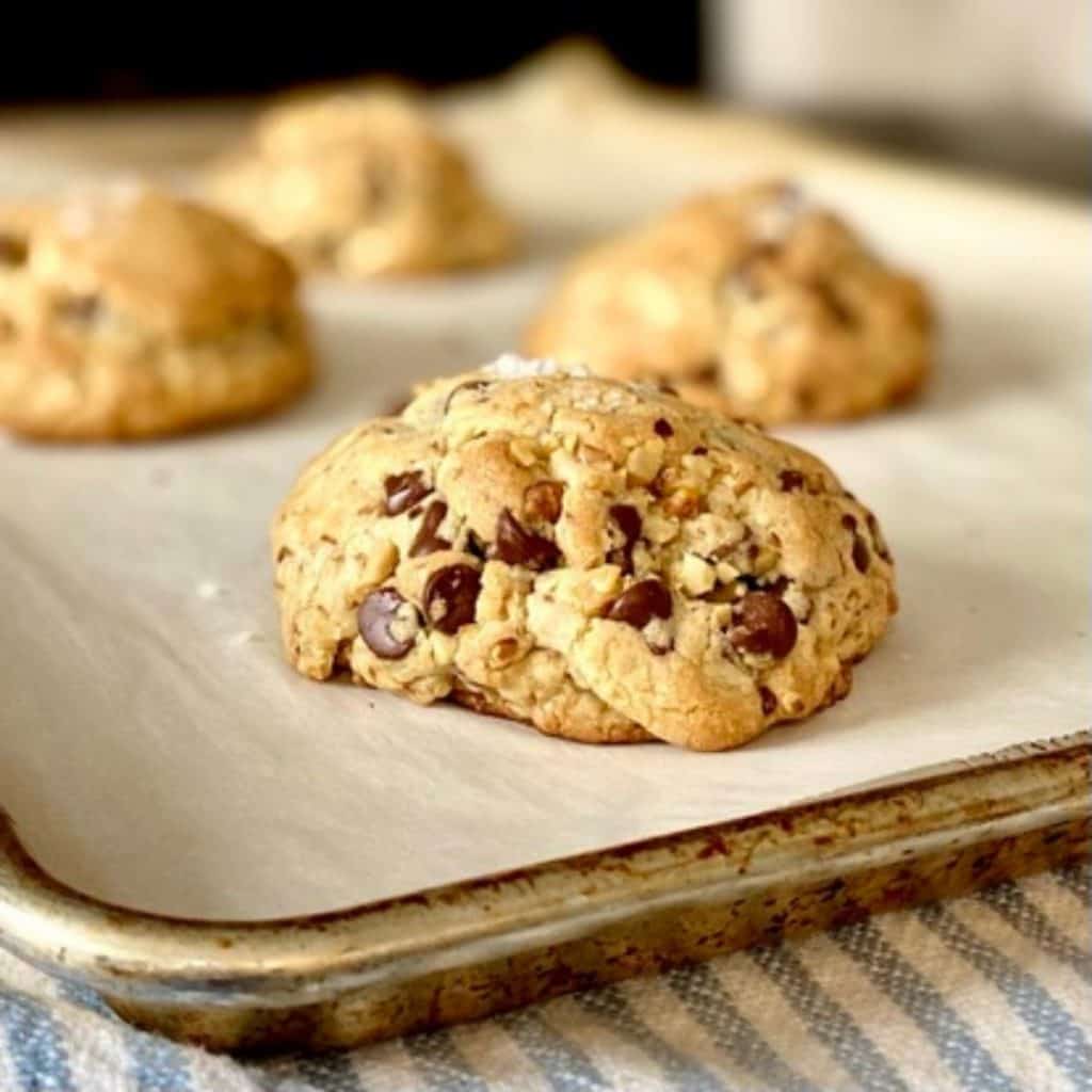 4 chocolate chip cookies on parchment lined baking sheet