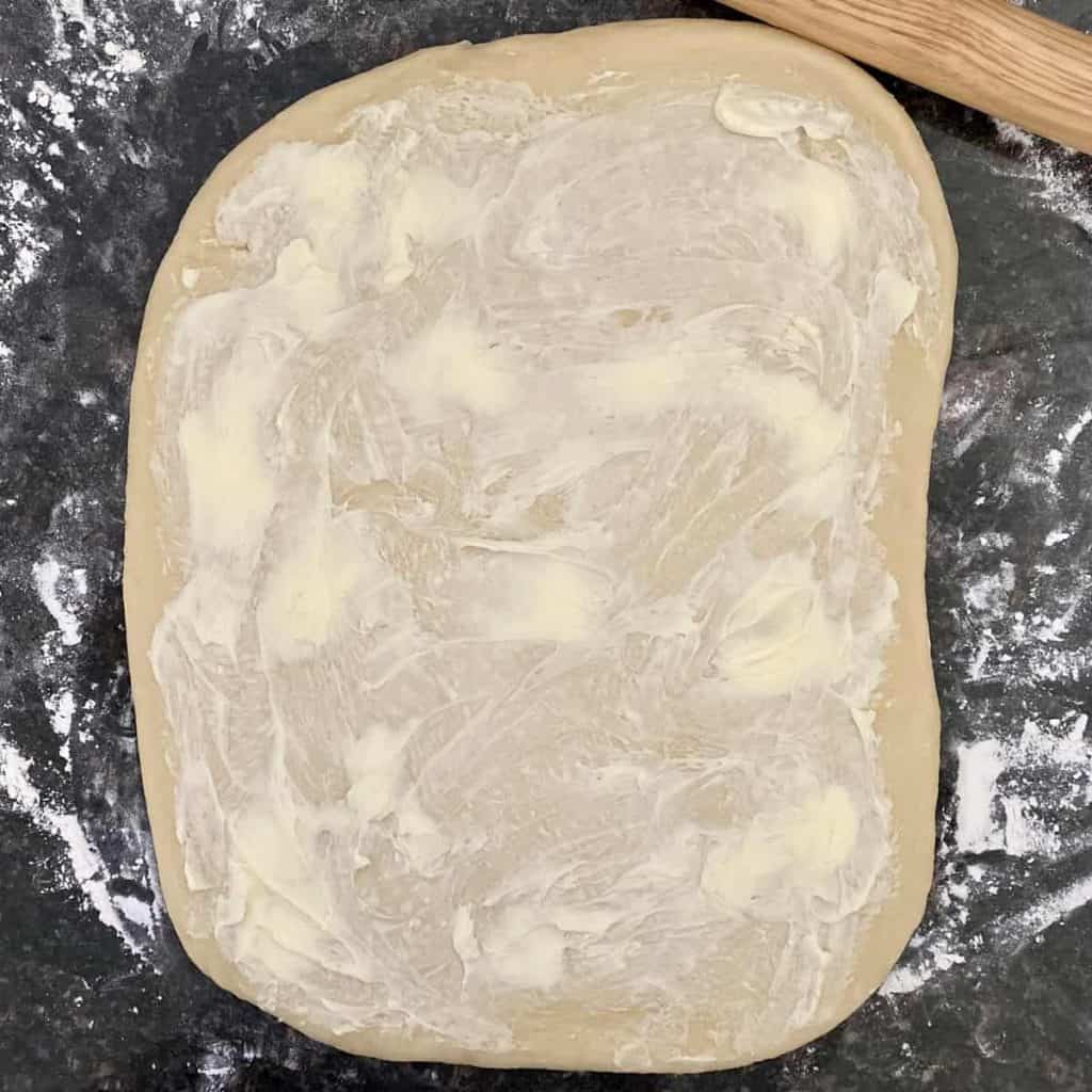cinnamon roll dough spread with butter on floured counter
