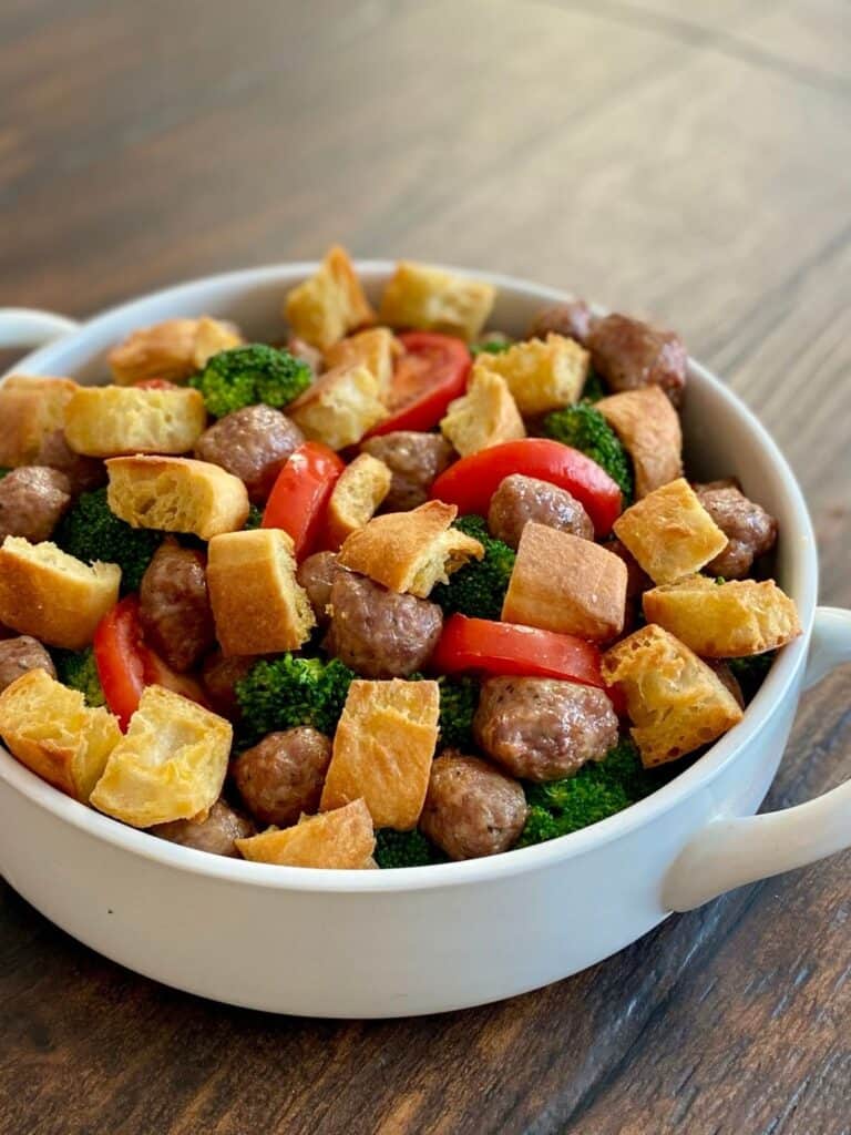 round white casserole dish filled with cooked broccoli, sausage, tomatoes and croutons
