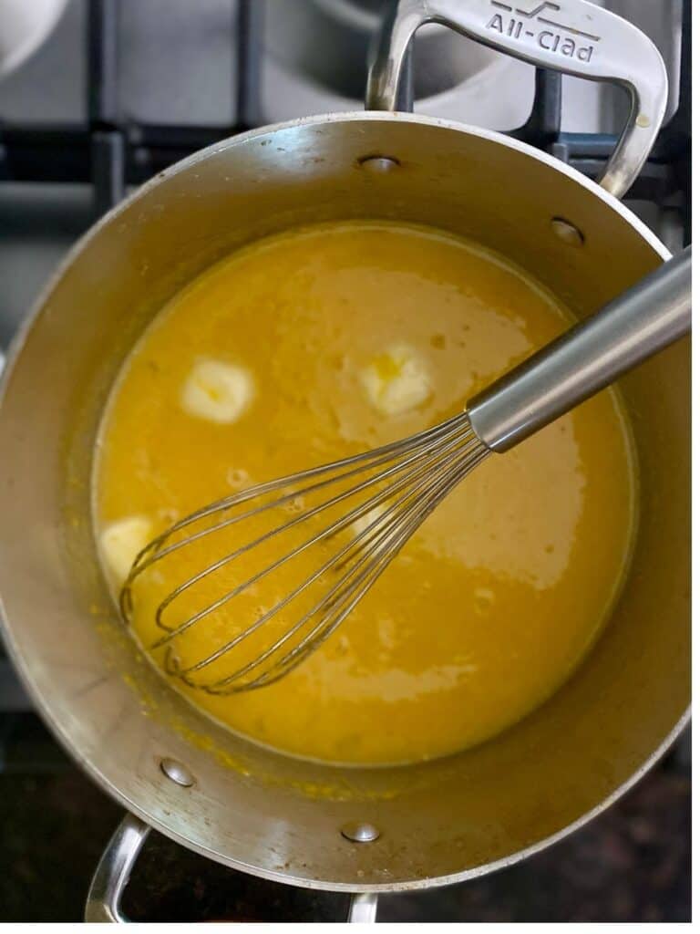 whisking butter into lemon filling in saucepan on stove top