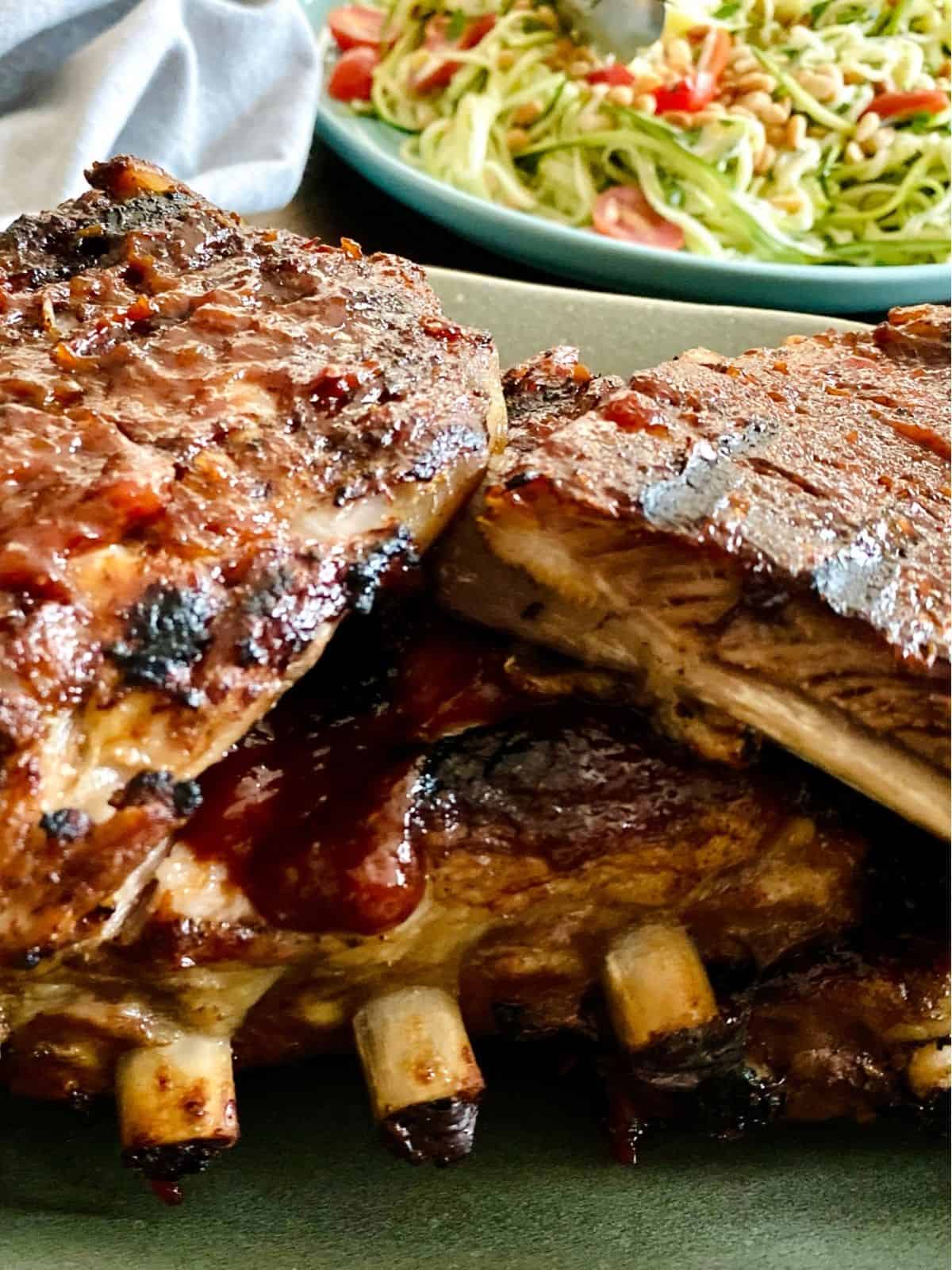 close up of bbq ribs with salad in the background