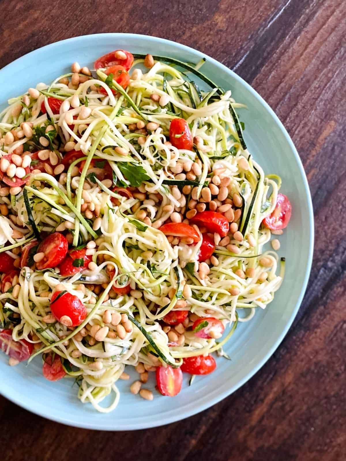 zucchini, tomato, pine nut salad in blue bowl