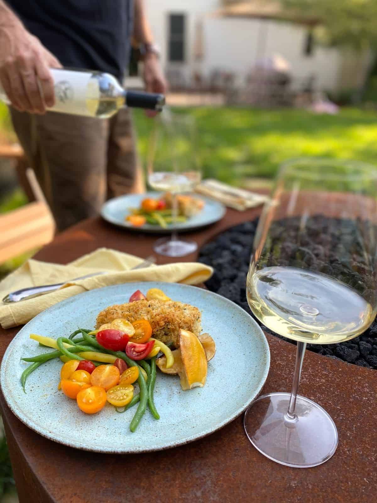 plated lemon basil rockfish with green beans and tomatoes next tp glass of wine