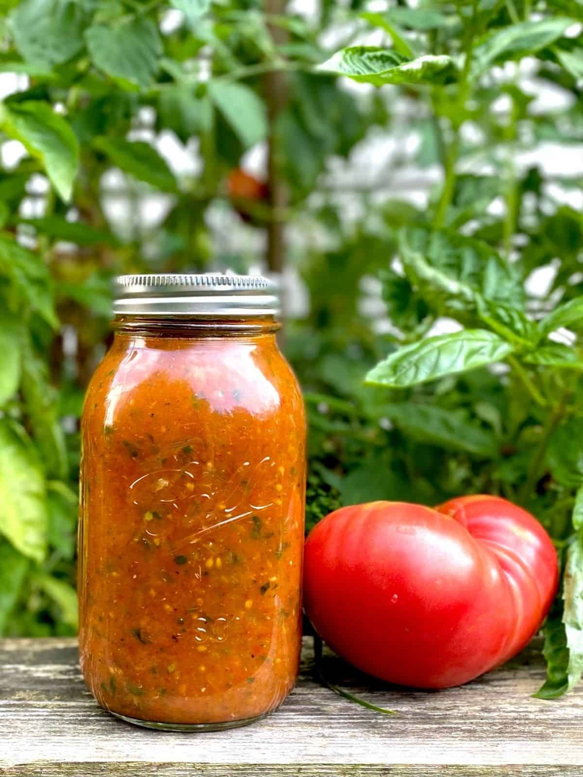 jar of roasted tomato sauce next to fresh tomato
