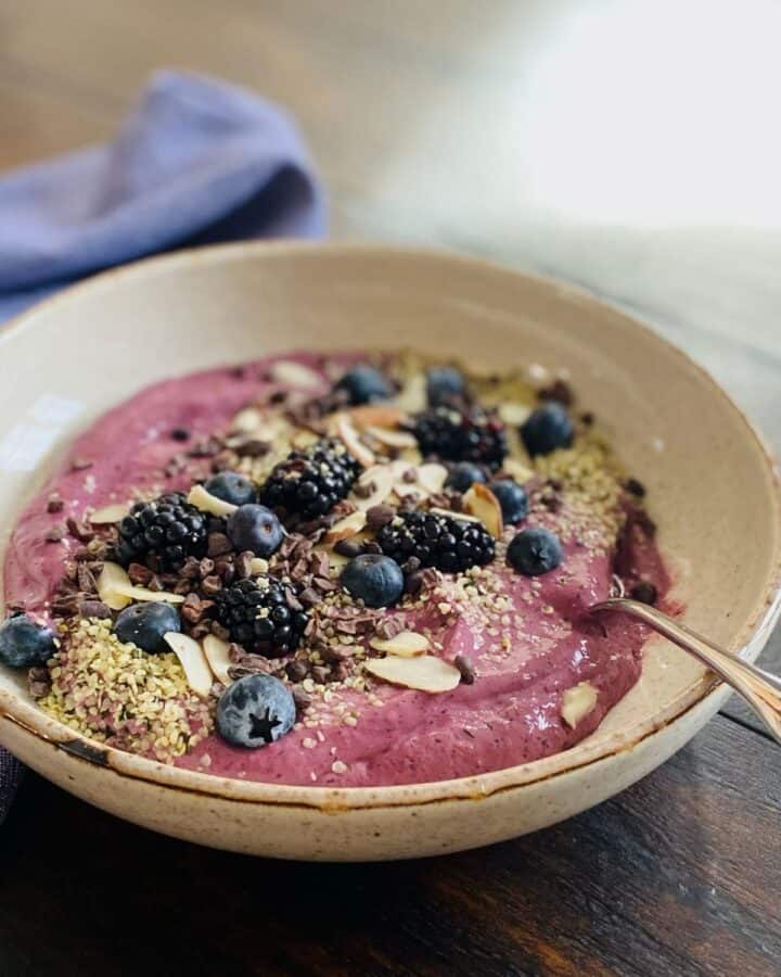 Glow Smoothie Bowl with spoon on wood table in front of blue napkin
