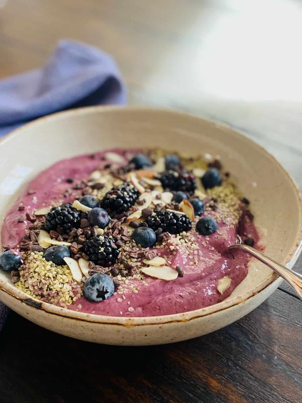 Glow Smoothie Bowl with spoon on wood table in front of blue napkin