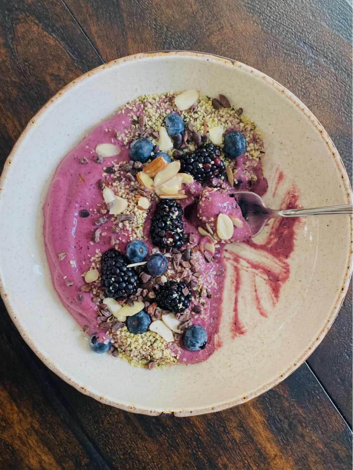 Partially eaten Glow Smoothie Bowl with spoon on wood table