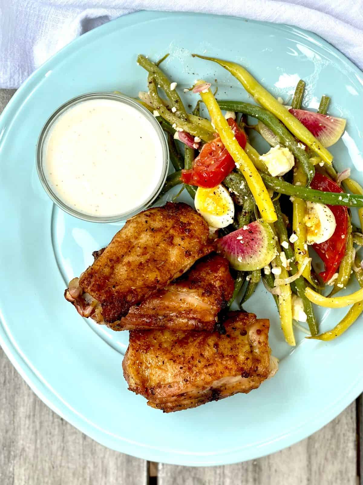 citrus rubbed chicken wings with feta cream and garden bean salad on blue plate