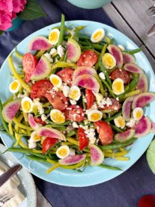mixed bean and watermelon radish salad with quail eggs on blue platter