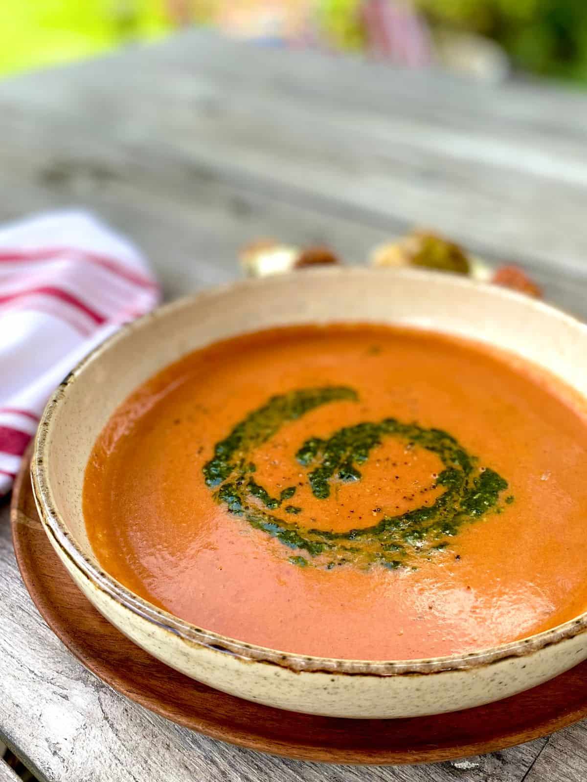 creamy tomato soup swirled with pesto in bowl with red and white napkin