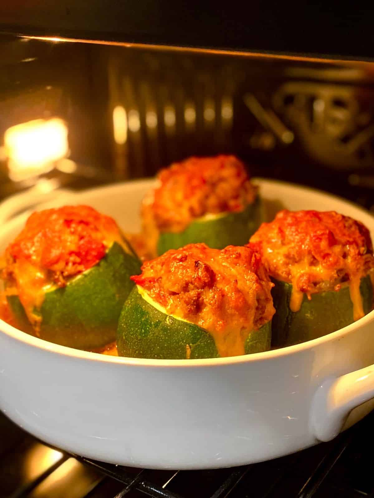 cheeseburger stuffed zucchini in casserole dish baking inside oven