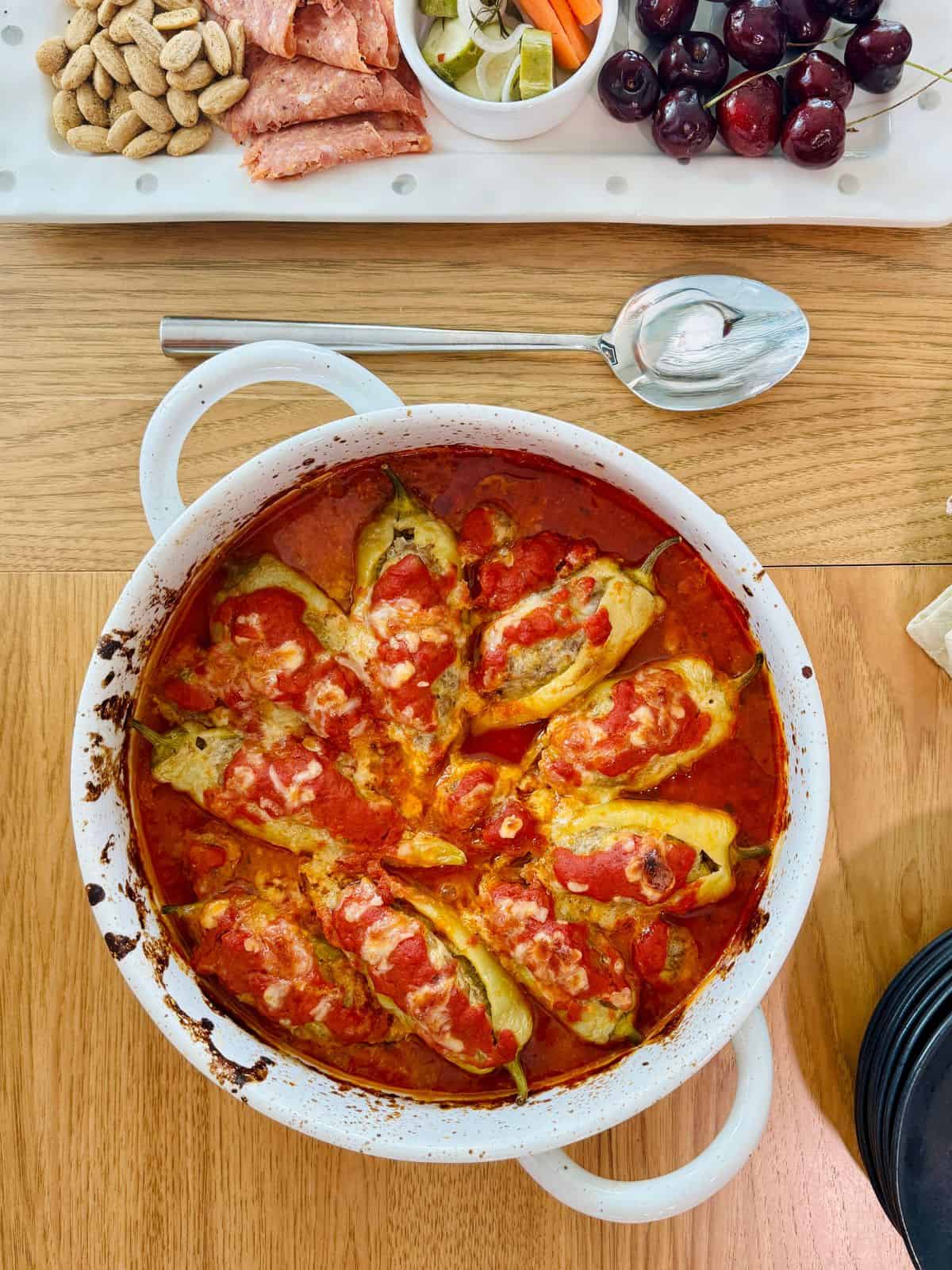 A table with a dish of cooked sausage stuffed pickled banana peppers